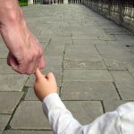 a man walking with his child catching only one finger of the childs' hand. body language. relationship
