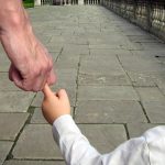 a man walking with his child catching only one finger of the childs' hand. body language. relationship